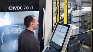 Mr Slimm at the control of the automated DMG Mori CMX 70 U VMC. The robot enclosure with safety fence and light curtain may be seen in the background. (Source: Whitehouse Machine Tools )