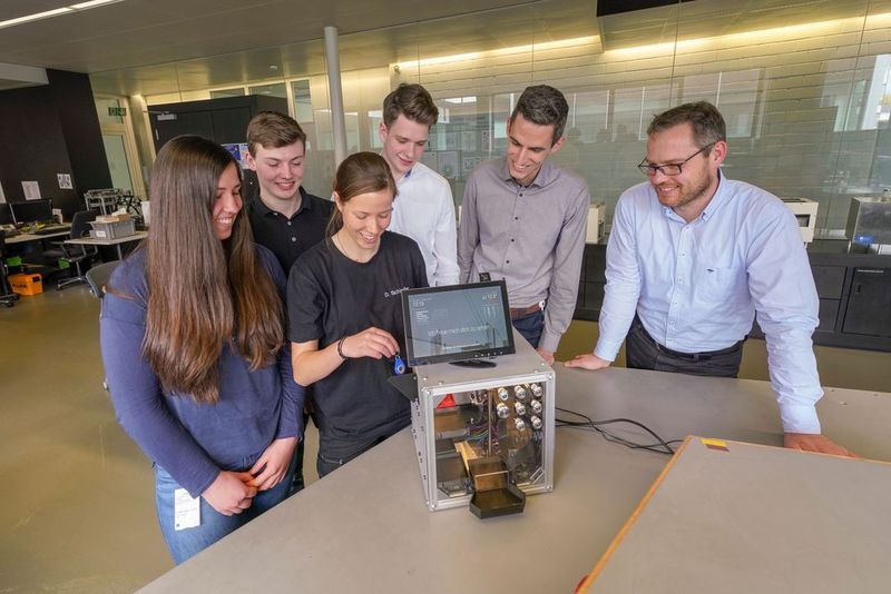 Studierende verschiedener Fachrichtungen der dualen Hochschule Baden-Württemberg entwickeln den Trumpf-Cube.  Im Bild v.l.n.r.: Livia Greisiger, Kai-Uwe Hüber, Daniela Schindler, Julian Gergen, Daniel Stannard (Digital Instructor) und Torsten Klaus (Head of Technical Apprenticeship) mit ihrem Digitalen Schlüsselkasten. (Trumpf/Weise)