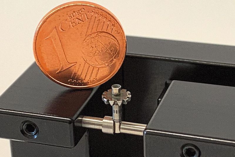 Im Vergleich mit einer Ein-Cent-Münze wird die Größenordnung der Prismenhalterung des Mikro-Reitstocks deutlich. (DK Fixiersysteme)