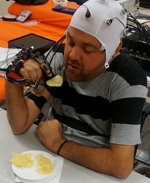 Hirnströme und Augenbewegungen des Probanden werden in Steuersignale übersetzt und an das Exoskelett übertragen, das die gelähmte Hand bewegt. (Surjo R. Soekadar)