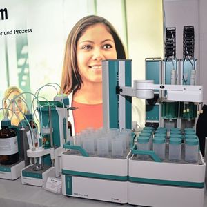 Autotitrator mit Probensampler: Der Omnis von Metrohm ist ein Titrationsroboter, der mit einem Probensampler ausgestattet werden kann. Ein greifarm nimmt sich dann die Proben und verschließt diese nach Entnahme wieder mit einem Deckel.