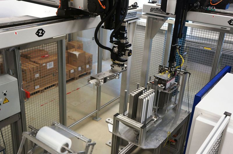 Aus der befüllten Magazinstation übernimmt ein zweites Handlinggerät jeweils einen Stapel und legt ihn in die Schlauchbeutel-Verpackungsstation ein. (Bild: Wittmann Battenfeld)