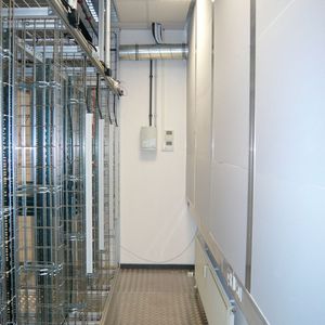 Beim Aufbau: Zwischen der Rückseite der Server-Racks (links) und der jetzt isolierten früheren Fensterfront (rechts) verläuft der Warmgang. An der Wand ist oben die Kühlmittelverbindung zu den Rückkühlern auf dem Dach des Bürogebäudes zu erkennen.(Foto:  Conect)