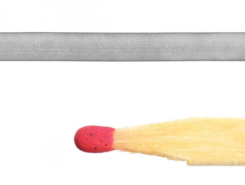 Unglaublich filigran: Ein aus Nitinoldrähten geflochtener Stent im Vergleich mit einem Streichholzkopf (Bild: Contrinex/Koerting)