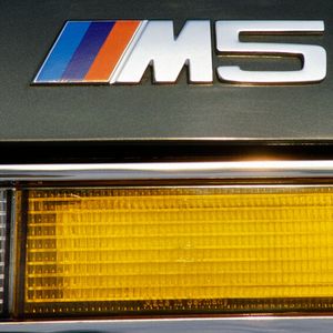 Morgens Rennstrecke, mittags Business-Lunch, dafür stand der 1985 eingeführte M5 laut BMW-Werbung. Die Magie des „M“ bemerkten auch die BMW-Händler, bei denen das in den Rennfarben blau, violett und rot gestaltete Emblem der BMW Motorsport GmbH zu den populärsten Ersatzteilen zählte: Das nur 20 Mark teure Teil zierte auch viele harmlose Basistypen wie den 518i oder 316 (E30).(Bild:  BMW)