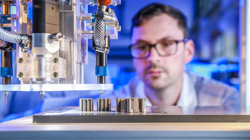 Johannes Rudolph überwacht im Labor den 3D-Multimaterialdruck einer elektrischen Maschine bei dem erstmals Kupfer, Keramik und Eisen gleichzeitig in einem Druckprozess zum Einsatz kommen. (TU Chemnitz/Jacob Müller)