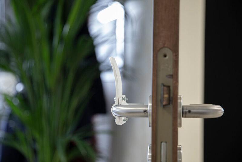 Der 3D-gedruckte Türöffner kann an vorhandenen Türgriffen befestigt werden.  (Materialise)