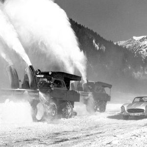 Zwei Mercedes-Benz Unimog der Baureihe 411 mit Schneefräse, angetrieben von einem zusätzlichen Motor auf der Pritsche. Im Vordergrund ein Mercedes-Benz 300 SL Roadster (W 198). Interessant auch die zusätzlich angebrachten „Überdachungen“ über den beiden Fahrzeugen.(Bild:  Daimler Truck)