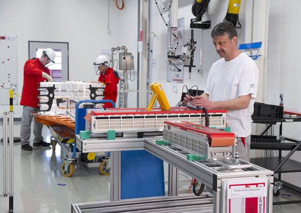 Vordergrund: Ein Mitarbeiter prüft die Spannungsabgriffe von Batteriezellen. Hintergrund: Elektrische Endmontage einer R8 e-tron Batterie. (Bild: Audi AG)