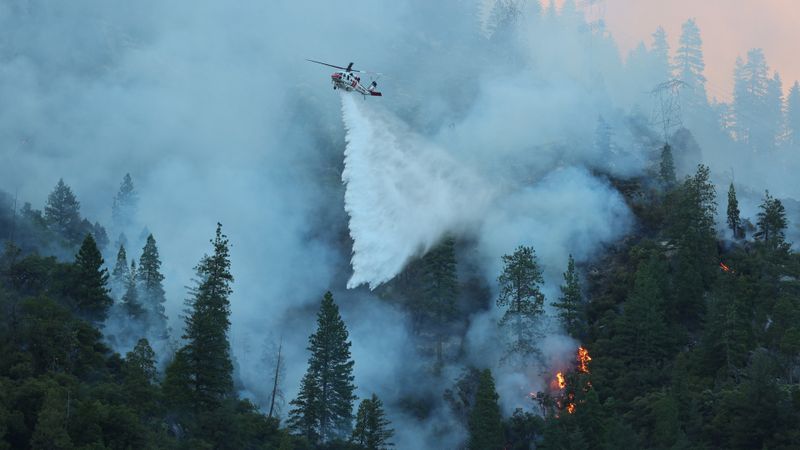 A Sikorsky S-70i Firehawk helicopter operated by CAL FIRE releases water over a burning hillside.(Source:  CAL FIRE / CC BY-NC 4.0)