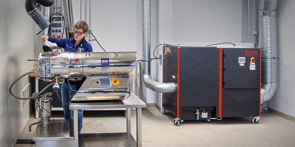 Der Entstauber Dustomat Dry von Esta erfasst via Absaugarm punktgenau die Stäube, die beim Befüllen des BHS-Horizontaltrockners entstehen.(Bild:  Esta)