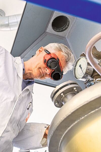 Gruppenleiter Martin Lerch schaut mit einer Schweißerbrille durch das Schauglas in den Kristallzüchtungsbehälter und kann so den Schmelzvorgang beobachten. (TU Berlin/PR/Felix Noak)