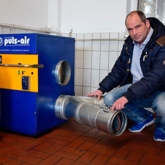 Marco Barnewold freut sich über den hohen Wirkungsgrad seiner Werkstattheizung. Ein zweites Rohr versorgt die Aufbereitungshalle mit Warmluft.       (Bild:  Rubbel)