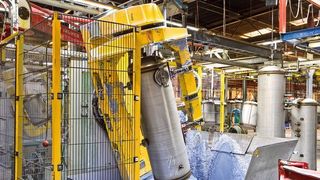 Die Lichtgitter im Einsatz: Der Bereich um den Einzelpositionierer ist von drei Seiten zugänglich. Im Hintergrund wird ein Behälter zugeführt. Nach erfolgter Bearbeitung übernimmt ein Greifer (rot) den Behälter. (Pilz GmbH & Co KG)