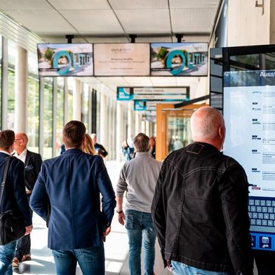 Visitors on the grounds of Messe Stuttgart use a large touchscreen information kiosk to call up the Online Exhibitor Directory (OED) for AMB. (Source: Messe Stuttgart)