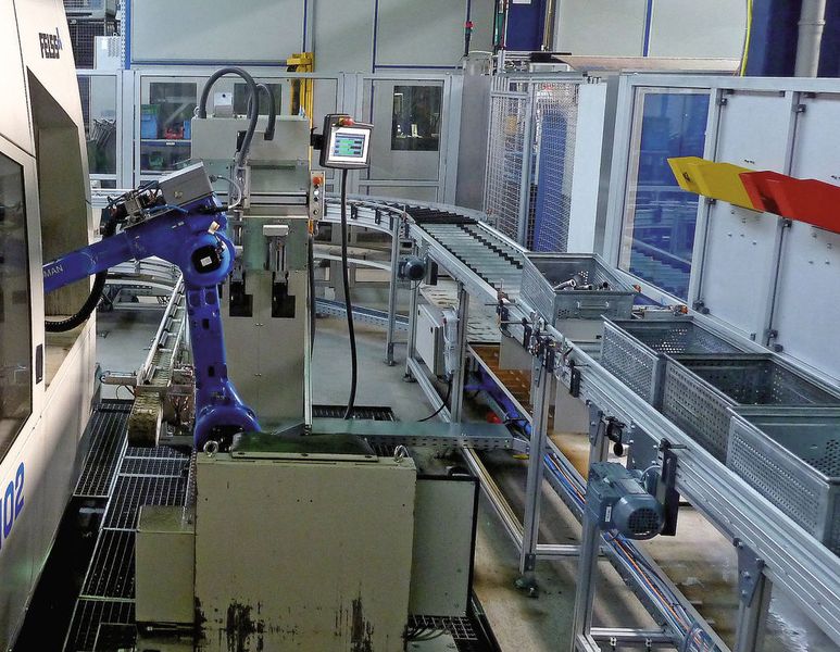 Bild 6: Die Be- und Entladung der Aximus geschieht über einen Roboter, der links  unten die Rohre entnimmt, sie in die  Maschine legt und die umgeformten Teile rechts in Behälter  ablegt.  (Bild: Kuhn)