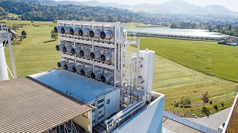 Die CO2-Filter Anlage von Climeworks und im Hintergrund das Gewächshaus in dem die Pflanzen mit dem CO2 gedüngt werden. (Julia Dunlop/Climeworks)