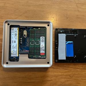 Der magnetisch befestigte Deckel gibt den Zugang zu den Steckplätzen für die DDR5-SO-DIMMs und die SSDs frei. Der kleine Barebone-Rechner fasst eine M.2-2280 und eine M.2-2242-SSD. Am Deckel sind Wärmeleitpads für die SSDs befestigt.(Bild:  Vogel IT-Medien)