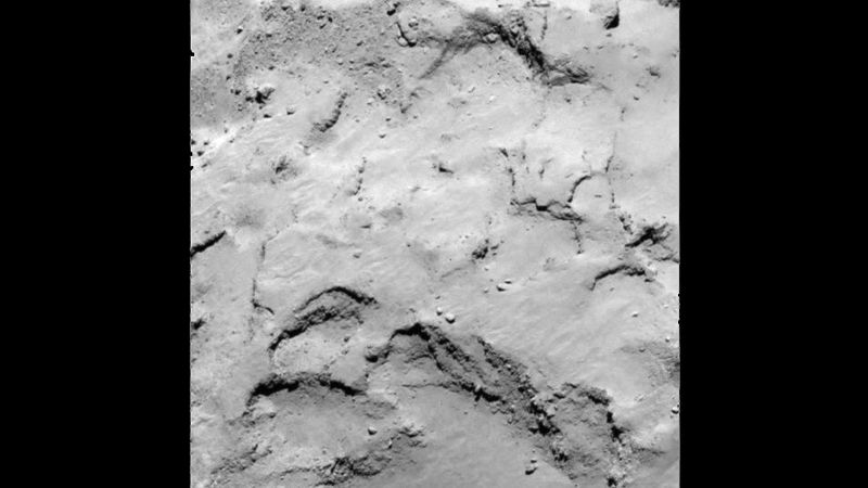 Landestelle J hat große Ähnlichkeit mit Landestelle I - die Landestelle sitzt ebenfalls auf dem kleineren Kometenteil, dem Kopf, hat interessante Oberflächenstrukturen und eine gute Beleuchtung bei der Rotation des Kometen. Für das Experiment Consert, bei dem Radiowellen durch den Kometen zum Orbiter gesendet und empfangen werden, ist diese Landestelle günstiger als Landestelle I. Da allerdings auch hier einige Felsbrocken und Terrassen zu sehen sind, sind höher aufgelöste Kamerabilder notwendig, um die Details des Geländes genauer zu bestimmen. (Bild: ESA)