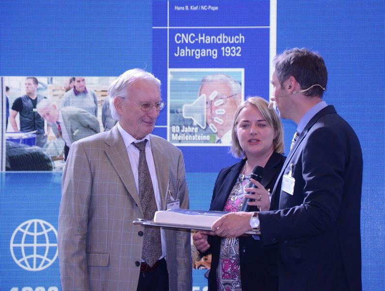 Der 80-jährige Hans B. Kief wird von Sandra Stoll und Frank Nolden für seine Verdienste und die Gründung des CNC-Handbuchs geehrt. (Michel)