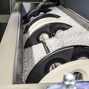 The workpiece holder is automatically lowered into the trough vibrator and placed into loops on the left and right. This allows it to move freely within the grinding media and be easily and automatically removed again.(Image: Rösler Oberflächentechnik GmbH)