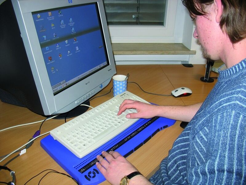 Jann Schneider ertastet den Bildschirminhalt in Punktschrift mit der Braillezeile - der Bildschirm ist seinen sehenden Kollegen vorbehalten, wenn es kurze Absprachen gibt. Bild: SSI Schäfer Noell (Archiv: Vogel Business Media)