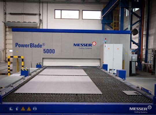 Die Laserschneidmaschine Powerblade mit Umhausung in der Produktionshalle in Tarnowskie Góry bei der Chemnet Group. Sie unterstützt nun bei der erfolgreichen Ausführung eines EU-geförderten Großprojekts und erweiterte außerdem das Machbarkeitsspektrum.(Bild:  Messer Cutting Systems)