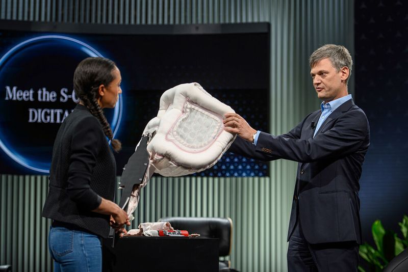 Michael Hafner, Leiter Automatisiertes Fahren, zeigt den neuen Fondairbag, dessen röhrenartiges Außenskelett hart aufgeblasen wird, während die Mitte flexibel bleibt. (Bild: Daimler)