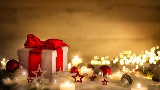weihnachten-hintergrund-mit-geschenk-und-rotem-band-kerzen-lichterkette-weihnachtsdeko-und-schnee-stockpack-adobe-stock-scaled (Quelle: Smileus - Adobe Stock)