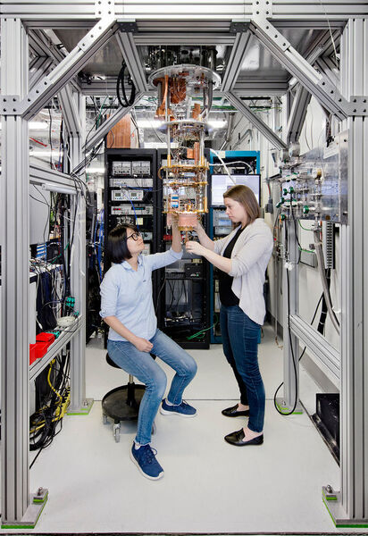 Und so sieht die gesamte Vorrichtung im IBM-Labor T. J. Watson Research Center in Yorktown aus. Hanhee Paik (links) and Sarah Sheldon schauen sich die Hardware in dem geöffneten Kühlschrank an, in dem die Chips auf Supraleitfähigkeit gekühlt werden müssen.   (IBM)