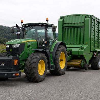 AgriBoost als zentrale Schnittstelle: Die elektrische Einheit verbindet Traktor, Hof und Anbaugeräte und ermöglicht eine flexible Nutzung elektrischer Energie für Antrieb und Arbeitsgeräte. (Bild: Universität Hohenheim / Daniel Wolpert (KI-generiert: AgriBoost-Einheit, Anhänger und Umgebung))