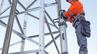 Das Bild zeigt den tragbaren High-Step-Lift im Einsatz an einem Hochspannungsmast, befestigt mit zwei High-Step-Schienen. (Bilder: Heinzmann)