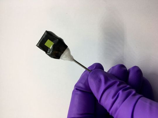 A standalone artificial leaf attached to a metal rod support. The photoanode side (green square) is visible in the photograph. A standalone artificial leaf attached to a metal rod support. The photoanode side (green square) is visible in the photograph.