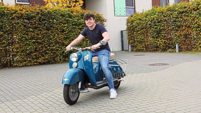 Die Herren mit den weißen Schläfen wissen es noch: Nicht nur Italien war eine Motorrollernation, sondern auch Deutschland, dessen Motorradindustrie in den Fünfzigern viele populäre Modelle hervorbrachte. Die Zündapp Bella gehörte von 1953 bis 1964 dazu, sie fand über 130.000 Käufer – einige davon sogar in Amerika, wo sie als „Suburbanette“ die Hausfrauen der Vorstadtsiedlungen mobil machen sollte. Diese Bella ist ein deutsches Exemplar mit Elektrostarter, gebaut 1957, als der Rollerboom schon wieder abflaute. Heute ermöglicht er ein Fahrerlebnis wie im Super-8-Film. Einmal so schwerelos fahren wie die jungen Paare im Filmlustspiel der Fünfziger: Bella macht’s möglich. Das Schmuckstück spendierte Hubert Hans. (Bild: Lebenshilfe Gießen)