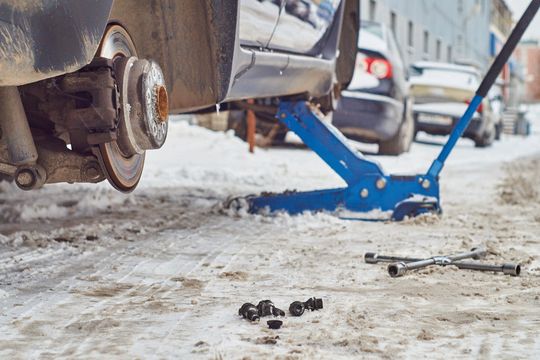 Ein Radwechsel ohne Hebebühne im Freien ist schon im lauen Frühling kein Spaß. Doch das Wetter hält auch noch Schnee, Starkregen, sommerliche Hitzewellen und Sturm bereit.(Bild:  © Georgy Dzyura - stock.adobe.com)