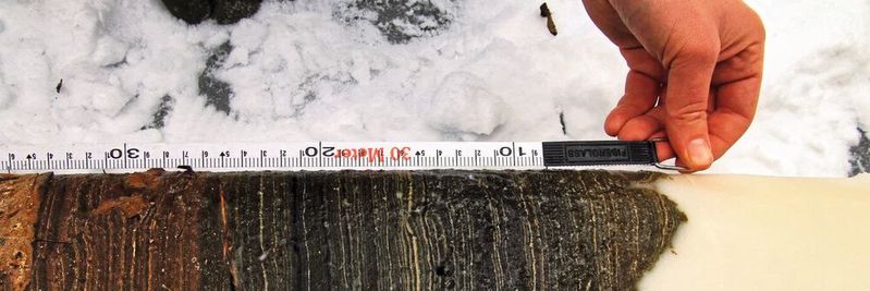 Bohrkern aus dem Crawford Lake: In dem kanadischen See verbinden sich bei Wärme Kalzium- und Karbonat-Ionen aus den Felsen im Wasser und kristallisieren zu kleinen Kalzitkristallen aus. Diese sinken langsam ab und bilden jeden Sommer eine weiße Schicht am Grund des Sees. Dadurch können Forscher genau feststellen, welches Jahr sie betrachten. Um das Jahr 1950 herum steigt der Anteil an Plutoniumteilchen in den Sedimenten deutlich an – ein klarer Hinweis auf menschliche Einflüsse und damit auf das Anthropozän. Bohrkern aus dem Crawford Lake: In dem kanadischen See verbinden sich bei Wärme Kalzium- und Karbonat-Ionen aus den Felsen im Wasser und kristallisieren zu kleinen Kalzitkristallen aus. Diese sinken langsam ab und bilden jeden Sommer eine weiße Schicht am Grund des Sees. Dadurch können Forscher genau feststellen, welches Jahr sie betrachten. Um das Jahr 1950 herum steigt der Anteil an Plutoniumteilchen in den Sedimenten deutlich an – ein klarer Hinweis auf menschliche Einflüsse und damit auf das Anthropozän.