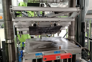 Die aufgeheizten Organobleche werden von einem Robotergreifsystem ins Spritzgusswerkzeug überführt.(Bild:  Fraunhofer IMWS)