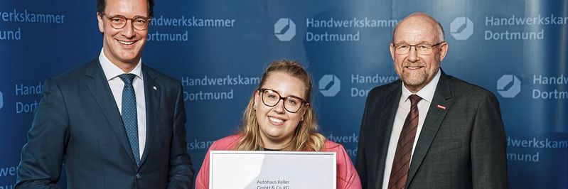 Ministerpräsident Hendrik Wüst (l.) und HWK-Präsident Berthold Schröder (r.) überreichten das Ausbildungssiegel an Helena Keller.