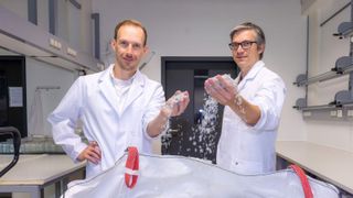 Dr. Ronny Frank (links) und Dr. Christian Sonnendecker vor einem Sack voll kleingehäckselten PET-Obstschalen, die darauf warten, mithilfe des Enzyms PHL7 in ihre chemischen Bausteine zerlegt zu werden. (Bild: Swen Reichhold/Universität Leipzig )