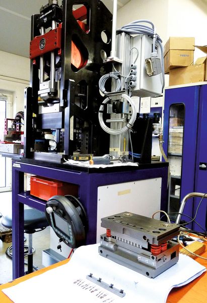 Montage einer TX-25-Stanzpresse mit C-Gestell und bereits montiertem AX-Modul, das in Systembauweise konzipiert ist und sich so zur optimalen Anpassung konfigurieren lässt. Daneben das Werkzeug und die herzustellenden Teile. (Bild: Kuhn)