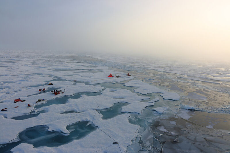 Abb. 2: Luftaufnahme arbeitender Polarforscher auf einer großen Eisscholle in der zentralen Arktis. Unter ihnen sind auch die Meereisphysiker, die ein Zelt errichtet haben, aus dem sie den Tauchroboter unter dem Eis steuern. (Bild: Stefan Hendricks, Alfred-Wegener-Institut)