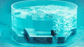 Demonstration der additiven Fertigung poröser Strukturen: Das metallische Logo des Fraunhofer ILT veranschaulicht die regulierbare Durchlässigkeit durch integrierte poröse Zonen, gesteuert mittels Knopfdruck. (Bild: Fraunhofer ILT)