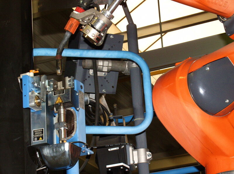 Mit der integrierten Brenner-Reinigungsstation hält die Roboteranlage ihre Gasdüsen automatisch sauber: Der Schweißdraht wird abgeschnitten und Trennmittel wird aufgebracht. Alle Vorgänge laufen zeitgleich mit dem Be- und Entladen der Vorrichtung ab. (Bild: Carl Cloos/Dieter Holler)