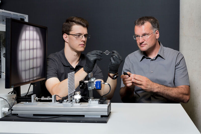 Optik auf dem Teststand: Sebastian Hägele und Andreas Heinrich (rechts) prüfen die Abbildungseigenschaften und Lichtstreuung einer dreidimensional gedruckten Flüssiglinse. (© Thomas Klink, Hochschule Aalen)