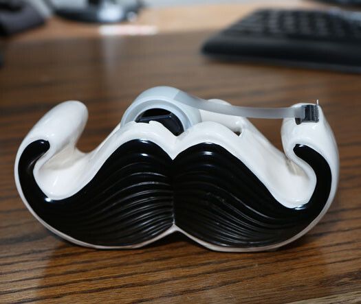 Respect the beard! Der Moustache-Klebebandroller schmückt jeden Schreibtisch und ist ein unverzichtbares Accessoire für männliche wie weibliche Bärte-Fans. Enjoymedia.ch vertreibt den Klebebandroller für knapp 23 Euro. (Bildquelle: Enjoymedia.ch)