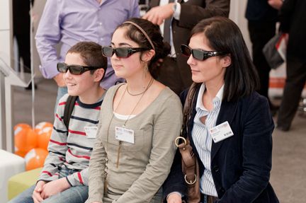 Eine Händlerin und ihre Kinder blicken gebannt durch die 3D-Brille am Telekom-Stand. (Archiv: Vogel Business Media)