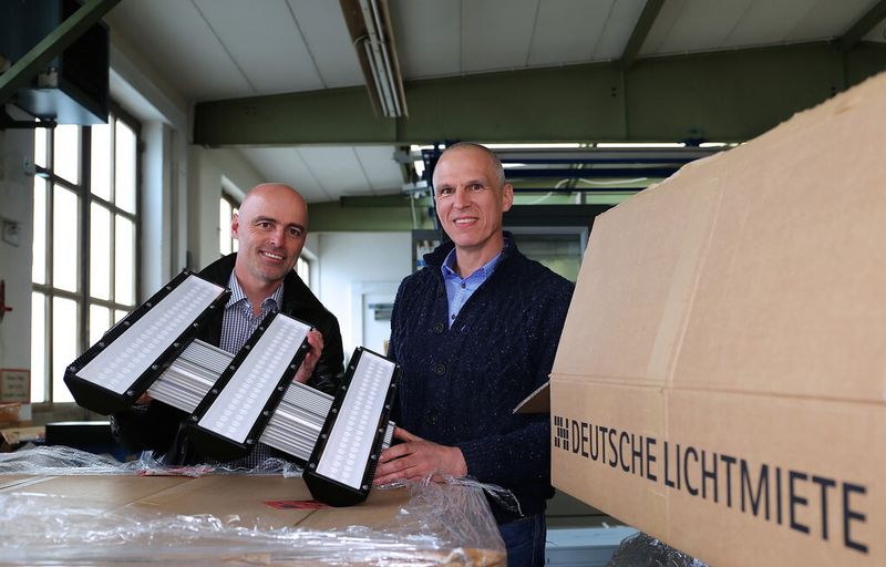 Die neuen dreiflammigen LED-Hallendeckenstrahler werden ausgepackt: Roman Teufl, Geschäftsführer Vertriebsgesellschaft Deutsche-Lichtmiete-Unternehmensgruppe, und Peter Andrä, Geschäftsführender Gesellschafter Riedl Aufzugbau GmbH & Co. KG. (Bild: Deutsche Lichtmiete)
