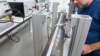 Versuchsaufbau zur Rohrprüfung, der auf der Hannover Messe zu sehen sein wird: Ingenieur Thomas Würtz kontrolliert den Aktor am Rohr, der ein Signal in die Rohrwand sendet. Ein anderer Aktor erlauscht dieses Signal: Anhand der Daten können die Forscher Rückschlüsse auf die Abnutzung des Rohres ziehen. (Bild: Oliver Dietze)