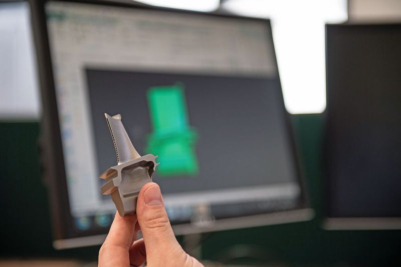 Die erste generativ gefertigte Turbinenschaufel «SGT400 Stage 1» (im Hintergrund die NX-Software) wurde von Materials Solutions, einem Siemens-­Service-Provider für die additive Fertigung, produziert. (Siemens)
