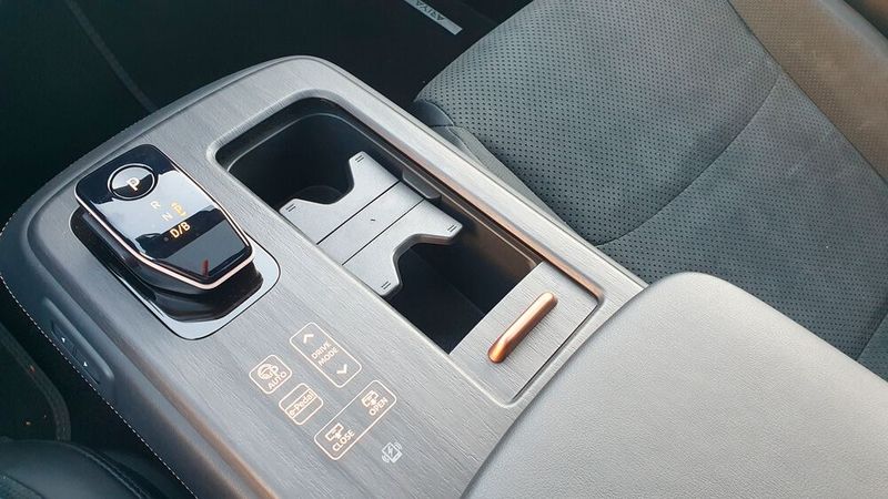 ... und in die schwebende, elektrisch verschiebbare Mittelkonsole. In letzterer befindet sich nicht nur der Wahlhebel. Der Fahrer kann hier unter anderem auch den gewünschten Fahrmodus auswählen und das E-Pedal betätigen. Tut er das, bekommt er zwar eine haptische Rückmeldung, dennoch schlägt hier die Optik die Funktionalität. Komisch ist, dass die Entwickler in der wuchtigen Konsole keinen Stauraum vorgesehen haben. Generell wurde mit Stauraum im Modell ziemlich gegeizt. Es gibt zwar unter anderem zwei Fächer, wovon sich eines von der Mittelkonsole aus elektrisch öffnen lässt, dennoch wären ein paar mehr Ablageflächen schön gewesen. (Bild: Mauritz – VCG)